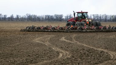 Kırmızı traktör tarlada dikiz aynasından, traktör tarlada tarla sürüyor. Büyük kırmızı traktör tarlada çalışıyor, hasat, iş, tarım. Toprak hazırlama, bahar mevsimi. Ukrayna