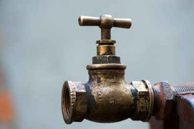 Eskimiş pirinç rengi musluk koyu bir arka planda izole edilmiş. Musluk vanası. Paslı bir borunun üzerindeki eski bakır musluk. Tesisat, onarım, sökme. yakın plan