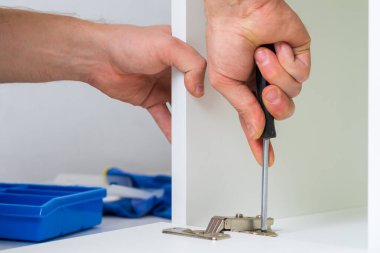 Mobilya montajı sırasında ön kapıya menteşe kurulumu. Seçili odak, bulanık arkaplan ve metin için alanı kopyala.