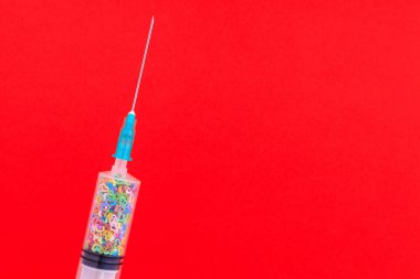 Sembolik kalplerle dolu tek kullanımlık klasik bir şırınga. Aşk konsepti. Metin için kopyalama alanı olan arkaplan. Kırmızı arkaplan.