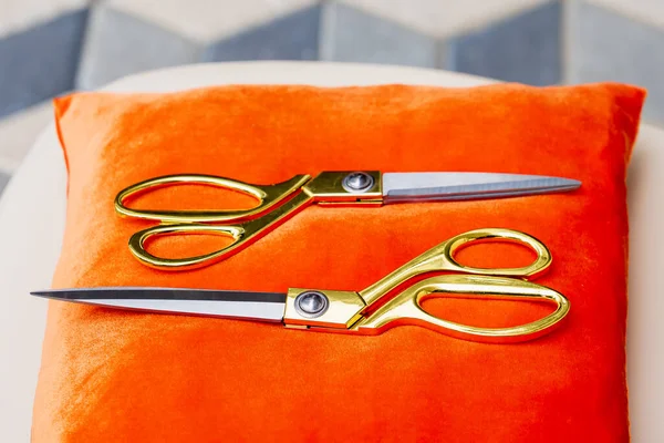 Golden scissors on a red pillow with selective focus and a blurred background. Startup and business grand opening concept.