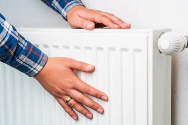 Ellerini ısıtma sisteminin radyatörüne koy, seçici odaklanma. Kopyalama alanı olan arkaplan