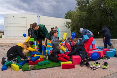 Children are captivated by huge soft bricks of a toy constructor in an urban environment at a city holiday. For editorial use. October 2, 2022 Balti Moldova.