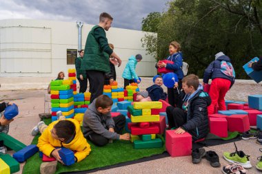 Children are captivated by huge soft bricks of a toy constructor in an urban environment at a city holiday. For editorial use. October 2, 2022 Balti Moldova.