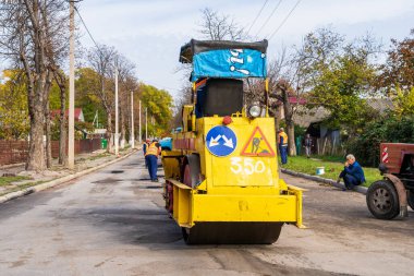 Asphalt paver of the road service on the repair of the road. Background with selective focus as copy space for text. October 25, 2022 Balti Moldova.