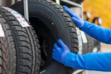 November 2, 2022 Balti Moldova. Hands of a worker in gloves who takes out car tires from a rack. Tire change season. Illustrative editorial, background