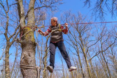 March 27, 2022 Mindrestii Moldova. Tourists amateurs train in the forest to walk on a rope. News editorial background