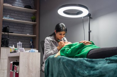 5 Ocak 2023 Balti Moldova. Makyöz kozmetik uzmanı takma kirpiklerle çalışır. Resimli yazı, arka plan