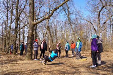 March 27, 2022 Mindrestii Moldova. Tourists lovers in the forest ride a rope. News editorial background