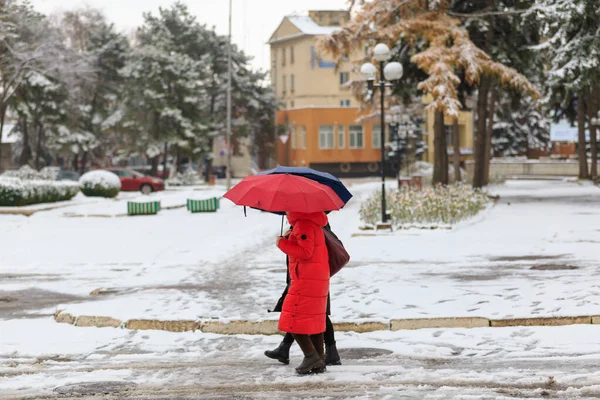 People with umbrellas during wet snow. Winter background with selective focus