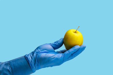 Doktorun elinde bir elma. Özenle seçilmiş bir arka plan. İzole edilmiş mavi tıbbi arkaplan
