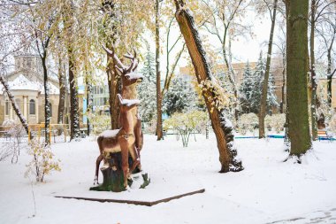 Parktaki geyik heykelinde kar var. Seçici odaklı kış arkaplanı