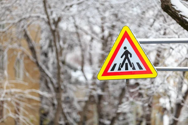 Snow on a road sign warning of pedestrians. Winter background with selective focus