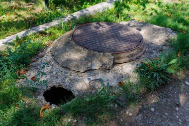 Kanalizasyon kapağının yanında asfalt tehlikeli bir çukur. Seçici odaklı arkaplan ve metin için alanı kopyala