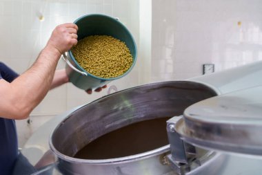 Bira fabrikasındaki fıçıya malt ekleme süreci, hareket bulanıklığı, bira demleme buharı. Seçici odaklı arkaplan ve metin için alanı kopyala