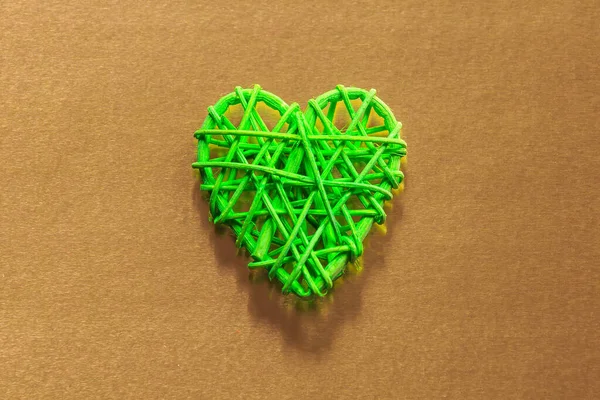 Wooden wicker heart. Rattan work in the shape of a heart. Love concept. Background with selective focus and copy space. On colored foil.