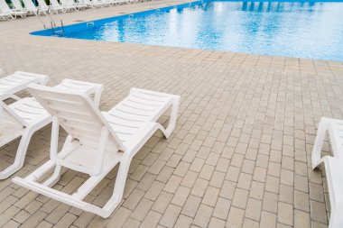 Havuzun yanındaki tatil köyünde boş güneş pansiyonları. Kopyalama alanı olan arkaplan