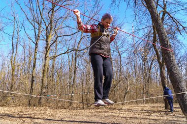 March 27, 2022 Mindrestii Moldova. Tourists amateurs train in the forest to walk on a rope. News editorial background