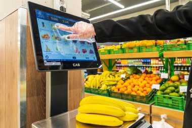 Bir kadın süpermarkette bir ölçekte muz ağırlığındadır. 13 Nisan 2023 Beltsy, Moldova. Resimli editoryal kullanım için.