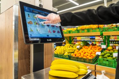 Bir kadın süpermarkette bir ölçekte muz ağırlığındadır. 13 Nisan 2023 Beltsy, Moldova. Resimli editoryal kullanım için.