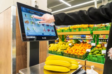 Bir kadın süpermarkette bir ölçekte muz ağırlığındadır. 13 Nisan 2023 Beltsy, Moldova. Resimli editoryal kullanım için.