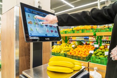 Bir kadın süpermarkette bir ölçekte muz ağırlığındadır. 13 Nisan 2023 Beltsy, Moldova. Resimli editoryal kullanım için.