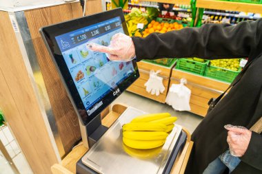 Bir kadın süpermarkette bir ölçekte muz ağırlığındadır. 13 Nisan 2023 Beltsy, Moldova. Resimli editoryal kullanım için.