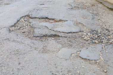 Yolda çukurlar var ve asfalt parçalanmış. Metin için kopyalama alanı olan arkaplan