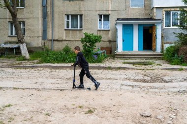16 Mayıs 2023 Beltsy, Moldova. Resimli editör kullanımı için. Bir çocuk bozuk bir yolda scooter sürüyor.