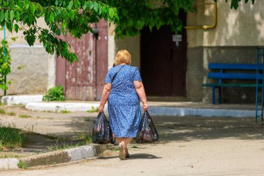 7 Haziran 2023 Beltsy, Moldova. Resimli editör kullanımı için. Ağır alışveriş torbalı bir kadın.