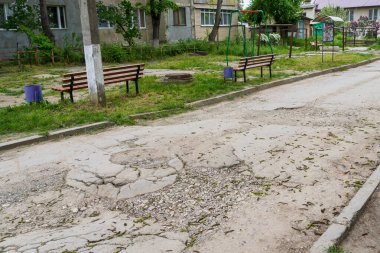 Yolda çukurlar var ve asfalt parçalanmış. Metin için kopyalama alanı olan arkaplan