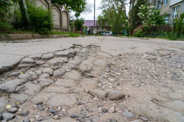 Yolda çukurlar var ve asfalt parçalanmış. Metin için kopyalama alanı olan arkaplan