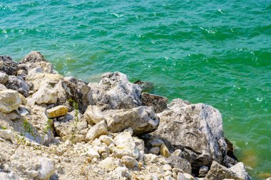 Taze bir rezervuarın kayalık kıyısı. Seçici odaklı arkaplan ve metin için alanı kopyala.