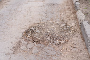 Yolda çukurlar var ve asfalt parçalanmış. Metin için kopyalama alanı olan arkaplan