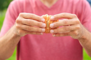 Bir adamın eli peynirli, abur cuburlu ve fast food konseptli mini puf böreği tutuyor. Bulanık arkaplan ve metin için kopyalama alanı olan ellere seçici odak.