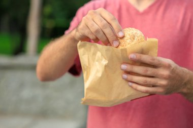 Adamın elinde mini ekmek, atıştırmalık ve fast food konsepti var. Bulanık arkaplan ve metin için kopyalama alanı olan ellere seçici odak.