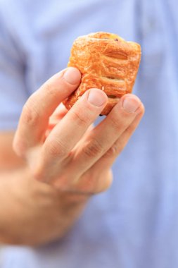 Bir adamın eli peynirli, abur cuburlu ve fast food konseptli mini puf böreği tutar. Bulanık arkaplan ve metin için kopyalama alanı olan ellere seçici odak.