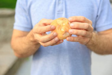 Adamın eli yuvarlak bir çörek, atıştırmalık ve fast food konsepti tutuyor. Bulanık arkaplan ve metin için kopyalama alanı olan ellere seçici odak.