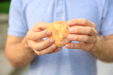 Adamın eli yuvarlak bir çörek, atıştırmalık ve fast food konsepti tutuyor. Bulanık arkaplan ve metin için kopyalama alanı olan ellere seçici odak.