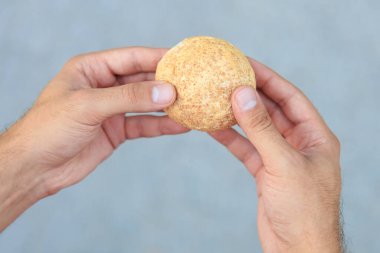 Adamın elinde mini ekmek, atıştırmalık ve fast food konsepti var. Bulanık arkaplan ve metin için kopyalama alanı olan ellere seçici odak.