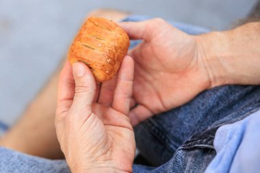 Bir adamın eli peynirli, abur cuburlu ve fast food konseptli mini puf böreği tutar. Bulanık arkaplan ve metin için kopyalama alanı olan ellere seçici odak.