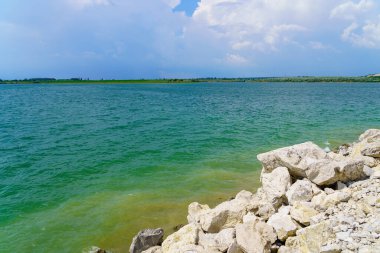 Taze bir rezervuarın kayalık kıyısı. Seçici odaklı arkaplan ve metin için alanı kopyala.