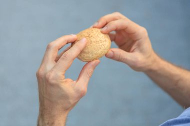 Adamın elinde mini ekmek, atıştırmalık ve fast food konsepti var. Bulanık arkaplan ve metin için kopyalama alanı olan ellere seçici odak.