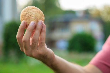 Adamın elinde mini ekmek, atıştırmalık ve fast food konsepti var. Bulanık arkaplan ve metin için kopyalama alanı olan ellere seçici odak.