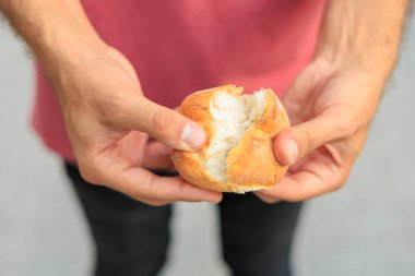 Bir adamın eli yuvarlak bir çörek, atıştırmalık ve fast food konseptini tutar. Bulanık arkaplan ve metin için kopyalama alanı olan ellere seçici odak.