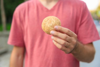 Adamın elinde mini ekmek, atıştırmalık ve fast food konsepti var. Bulanık arkaplan ve metin için kopyalama alanı olan ellere seçici odak.