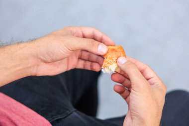 Bir adamın eli peynirli, abur cuburlu ve fast food konseptli mini puf böreği tutar. Bulanık arkaplan ve metin için kopyalama alanı olan ellere seçici odak.