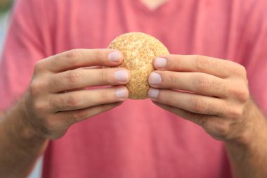 Adamın elinde mini ekmek, atıştırmalık ve fast food konsepti var. Bulanık arkaplan ve metin için kopyalama alanı olan ellere seçici odak.