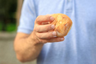 Adamın eli yuvarlak bir çörek, atıştırmalık ve fast food konsepti tutuyor. Bulanık arkaplan ve metin için kopyalama alanı olan ellere seçici odak.