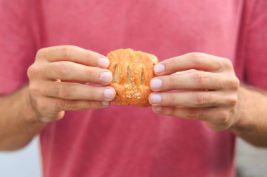 Bir adamın eli peynirli, abur cuburlu ve fast food konseptli mini puf böreği tutuyor. Bulanık arkaplan ve metin için kopyalama alanı olan ellere seçici odak.